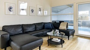 Un salon moderne avec un canapé d’angle, une table basse et des œuvres d’art encadrées accrochées au mur.
