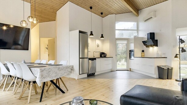 Une cuisine moderne dotée d’un four encastré, un coin repas avec une table en marbre et un canapé en cuir noir.