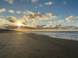 A beach with a clear sky and the sun setting or rising.
