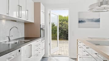 Une cuisine moderne avec des meubles blancs, un lave-vaisselle Bosch et une vue sur l’extérieur.