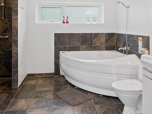 A bathroom with a freestanding bathtub, a toilet, and a shower. - Holiday Home in Blokhus (Blokhus)