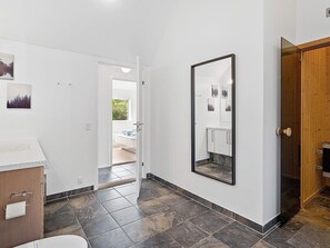 A hallway with a bed, a mirror, and a wooden door. - Holiday Home in Blokhus (Blokhus)