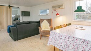 A modern living room with a grey sofa, a white floral table, and a red floor lamp. - 7 Person Holiday Home in Frederikshavn (Frederikshavn)