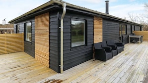 A modern cabin with a deck, large windows, and a chimney. - 7 Person Holiday Home in Frederikshavn (Frederikshavn)