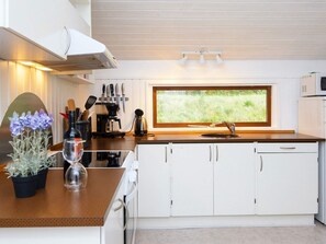 A modern kitchen with white cabinets, a large window, and a view of greenery outside. - 6 Person Holiday Home in Farvang (Farvang)