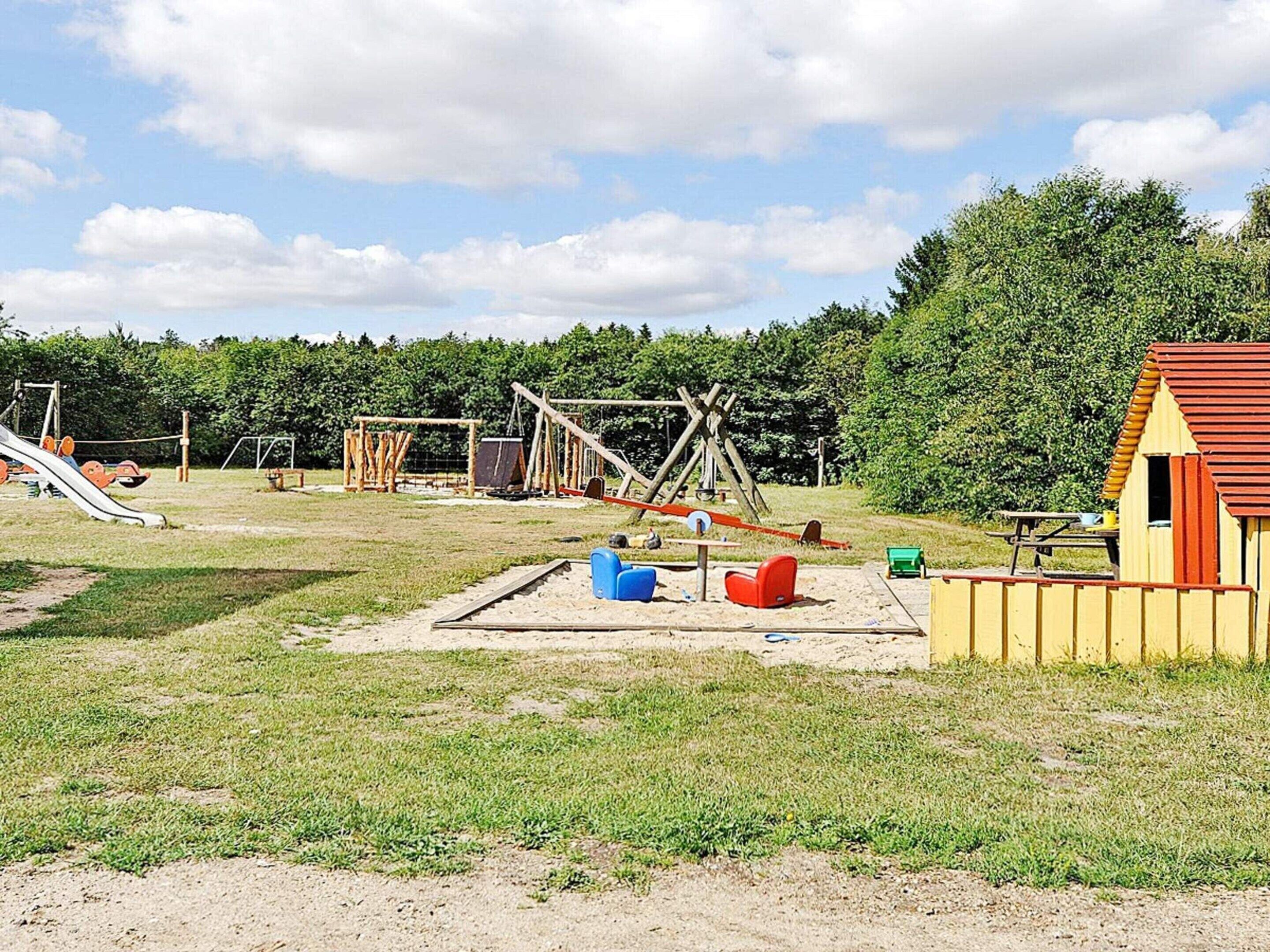A playground with various play structures, a small building, and a picnic table.