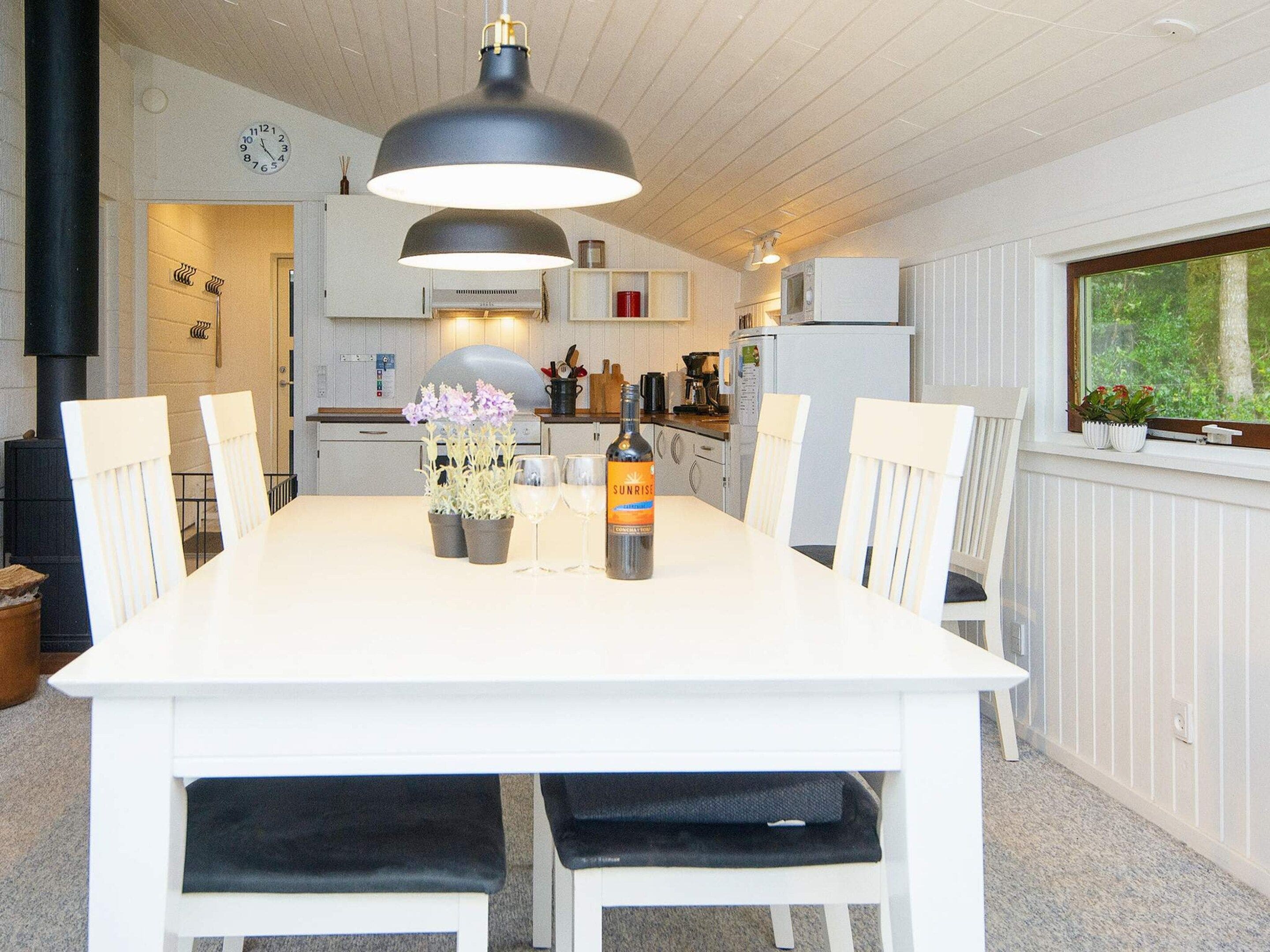 A modern kitchen with white cabinetry, a dining table with chairs, and a large pendant light.
