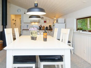 A modern kitchen with white cabinetry, a dining table with chairs, and a large pendant light.