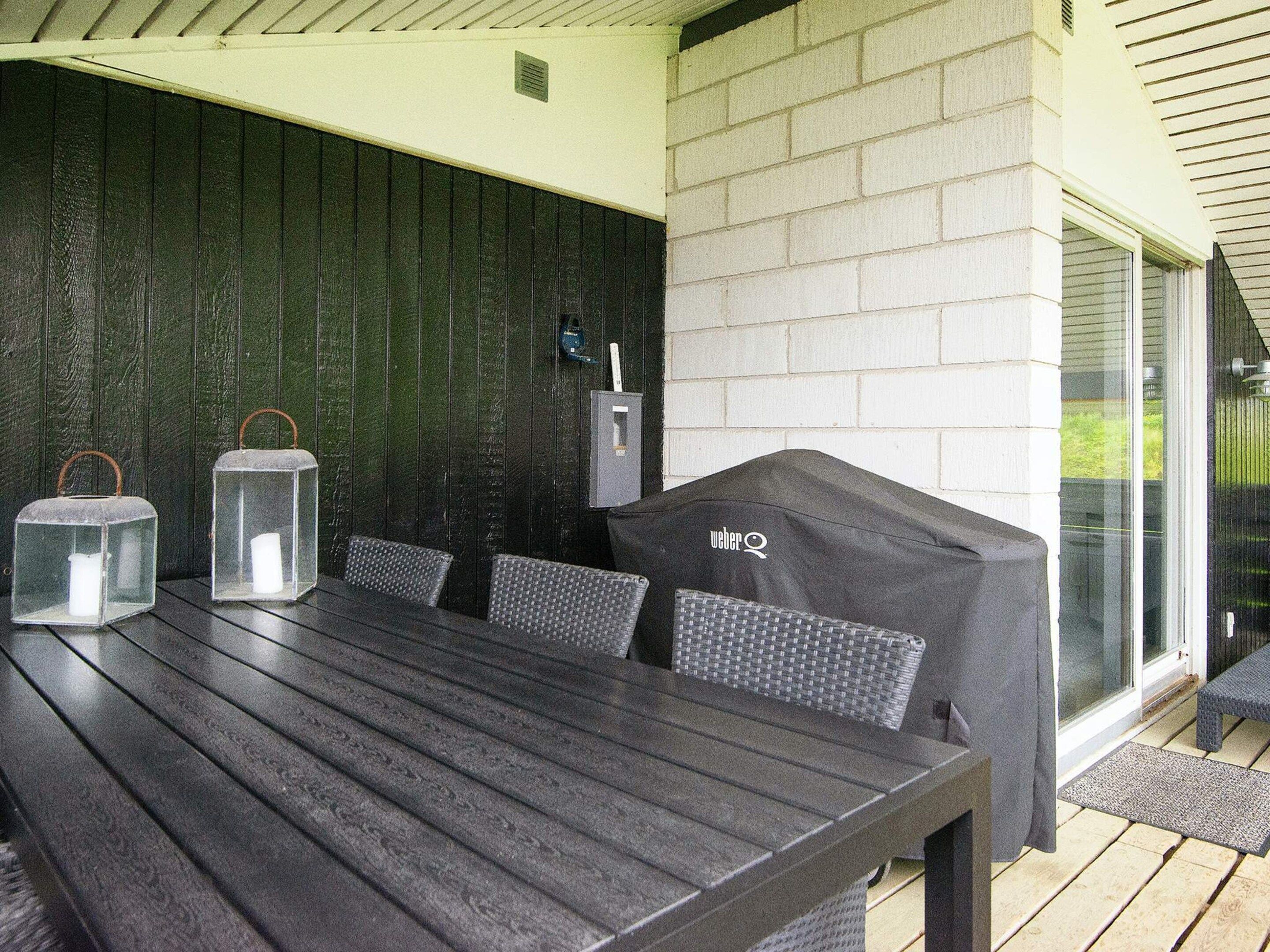 Patio esterno con tavolo e sedie, un barbecue e lanterne.