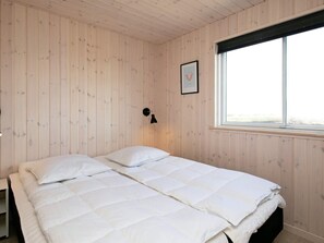 Ett rum med en säng, en vägglampa och ett fönster.