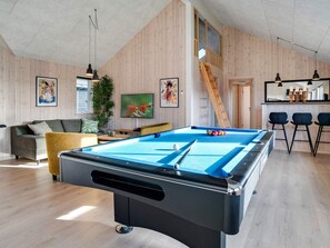 A pool table in a room with wooden walls, a sofa, a bar area, and a staircase. - Holiday Home in RingkÃ¸bing (Ringkobing)