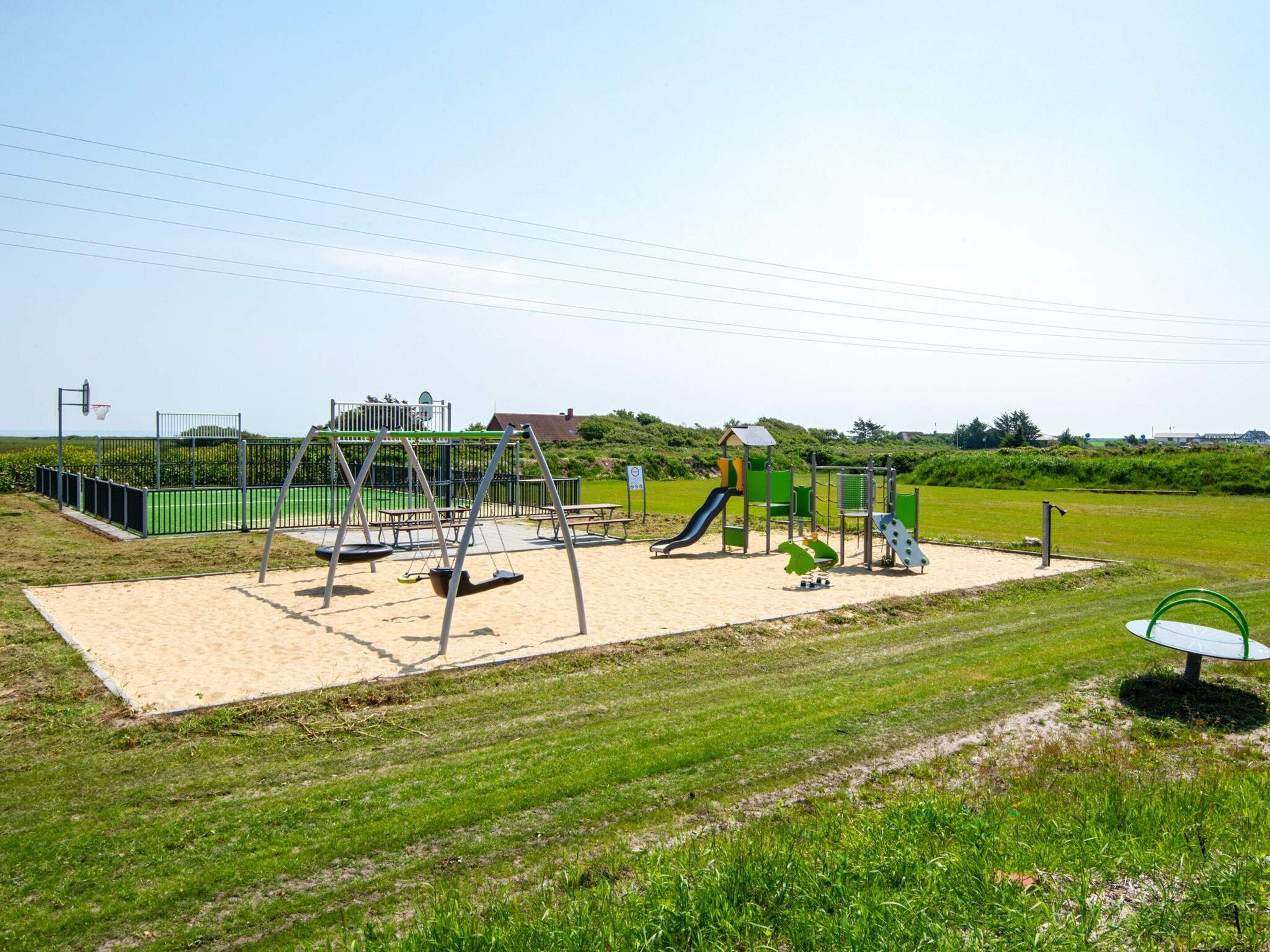 A playground with swings, slides, and a basketball hoop.