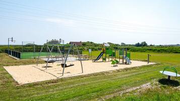 A playground with swings, slides, and a basketball hoop.