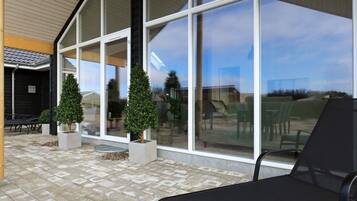 A modern outdoor seating area with a lounge chair and two potted plants.