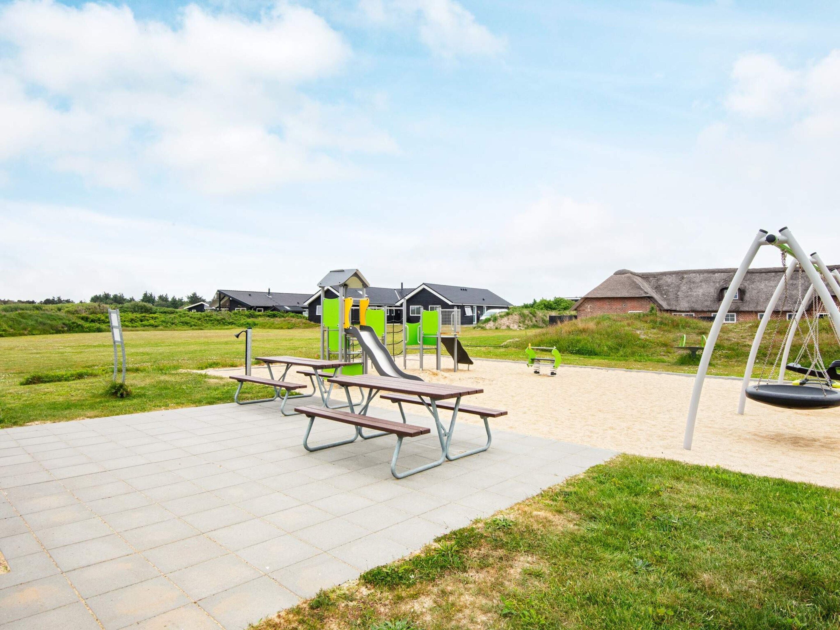 An outdoor playground with swings, slides, and picnic tables.