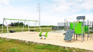 Een speeltuin met schommels, een glijbaan en klimconstructies.