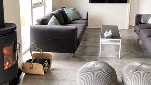 Ein Wohnzimmer mit einer Couch, einem Flachbildfernseher, einem Kamin und einem Couchtisch.