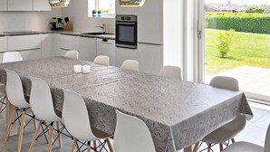 Eine moderne Küche mit Essbereich, großen Fenstern und Blick auf den Garten.