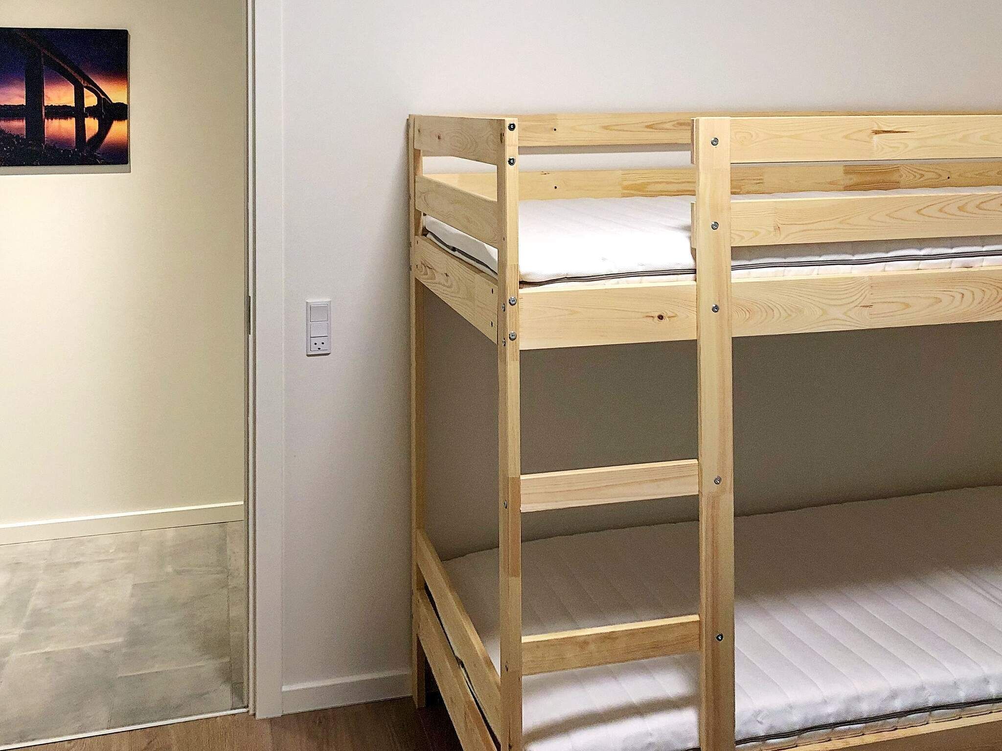 Ein Etagenbett mit Holzrahmen und weißer Bettwäsche.
