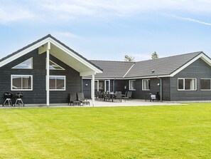 A modern building with a covered patio area and a lawn.