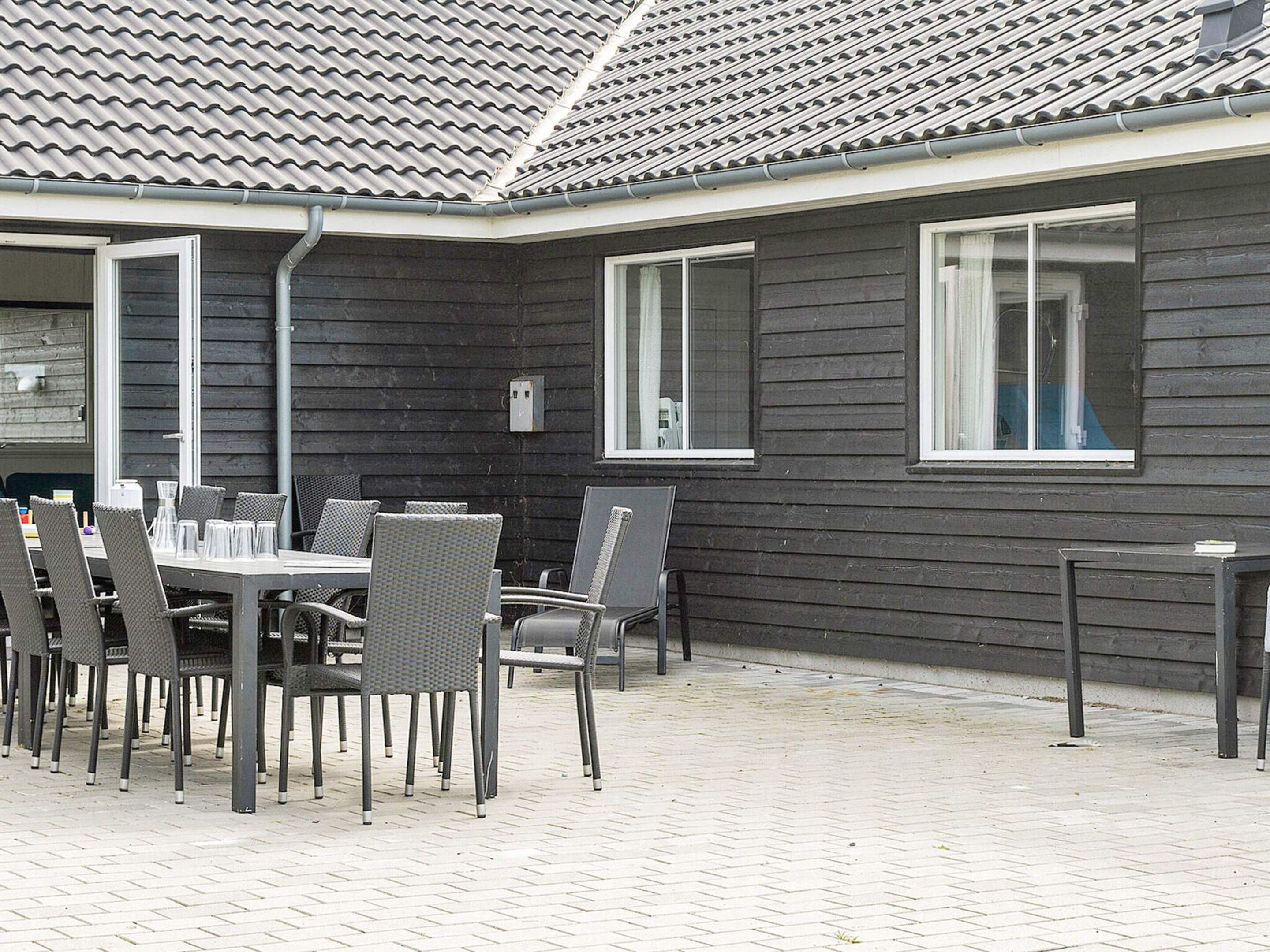 Un espace extérieur aménagé en terrasse, avec une table et des chaises, un toit en tuiles et une fenêtre.