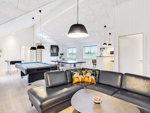 Uma sala de estar moderna com mesa de bilhar, sofá e mesa de pingue-pongue.