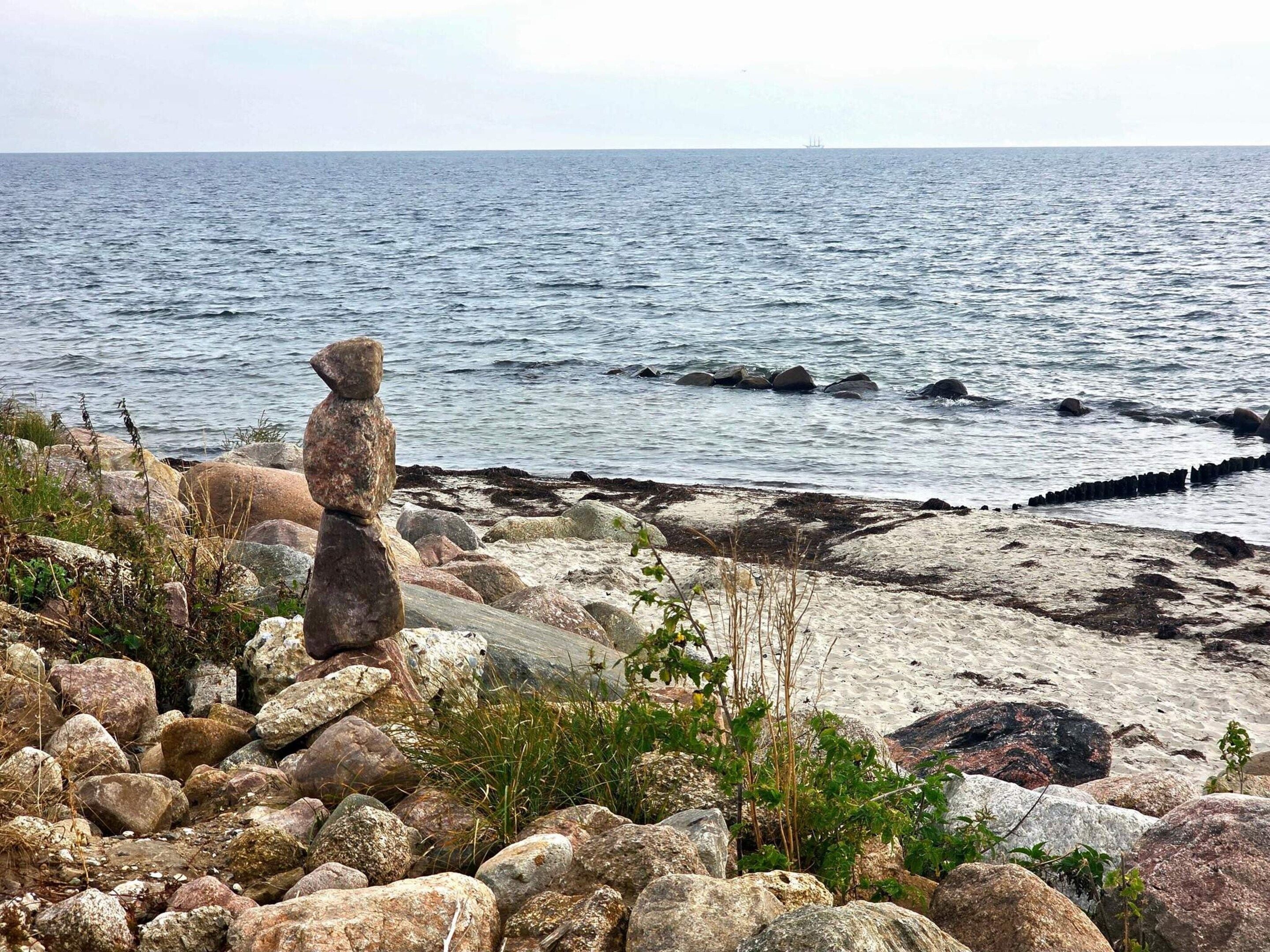 A rocky shoreline with a stone structure, possibly a cairn, overlooking the sea.