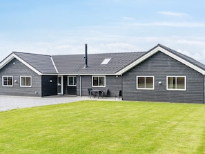 Ett modernt hus i två våningar med ett sluttande tak, en veranda med ett bord och stolar samt en välskött gräsmatta.