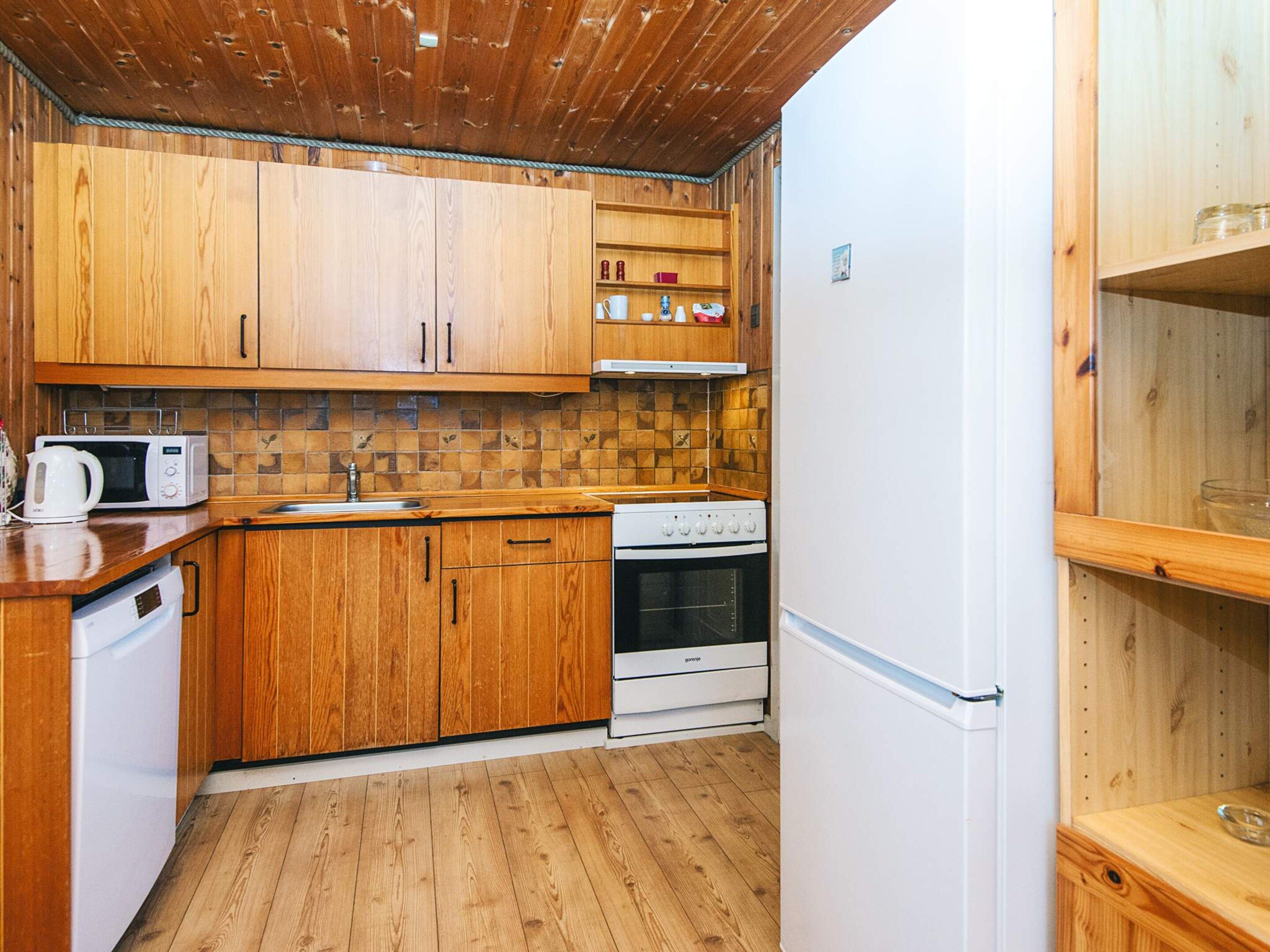 Una cocina compacta con armarios de madera, microondas, estufa y refrigerador.