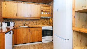 Una cocina compacta con armarios de madera, microondas, estufa y refrigerador.