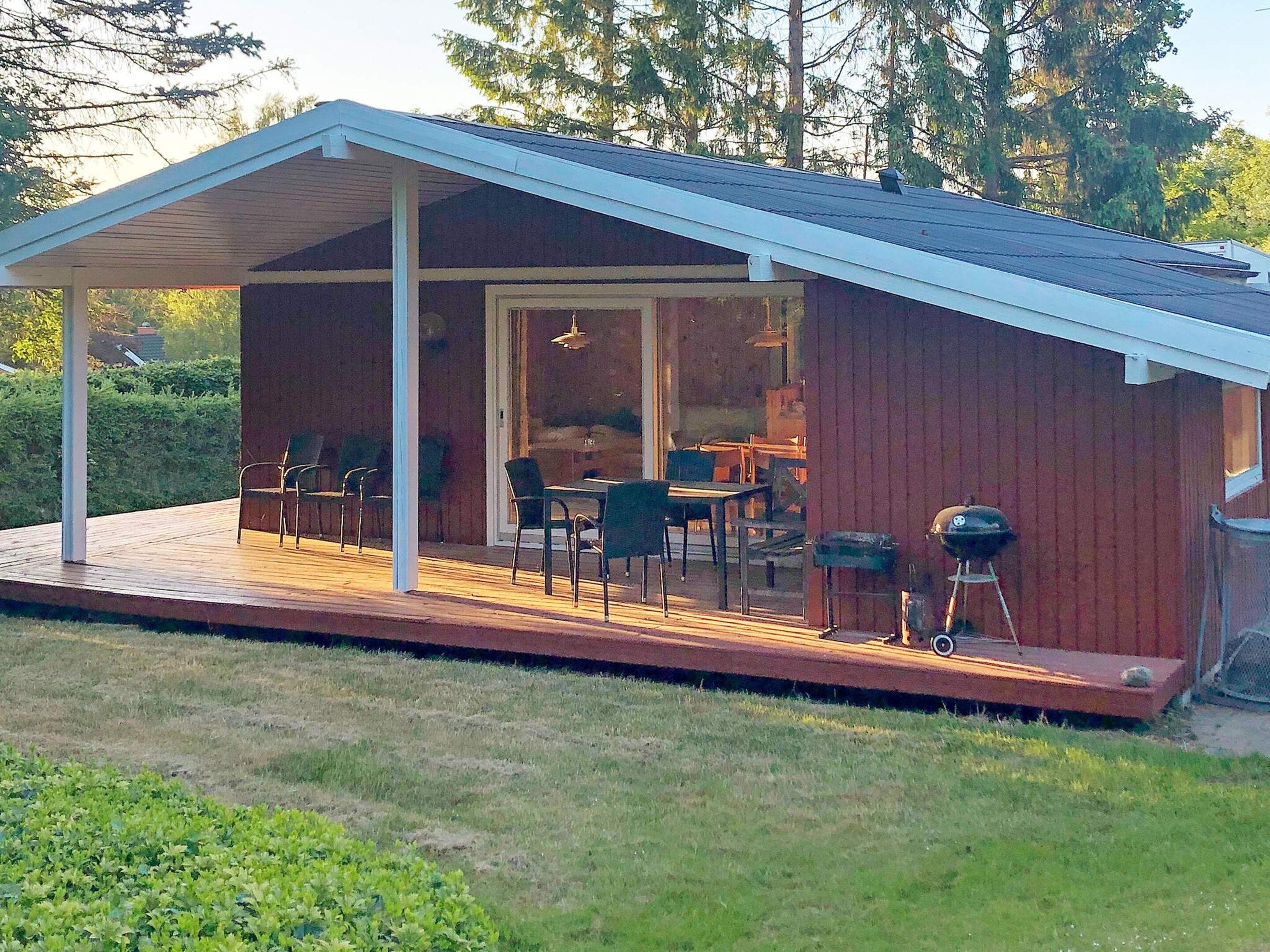 A covered outdoor area with a dining table and chairs, a grill, and a view of the interior.