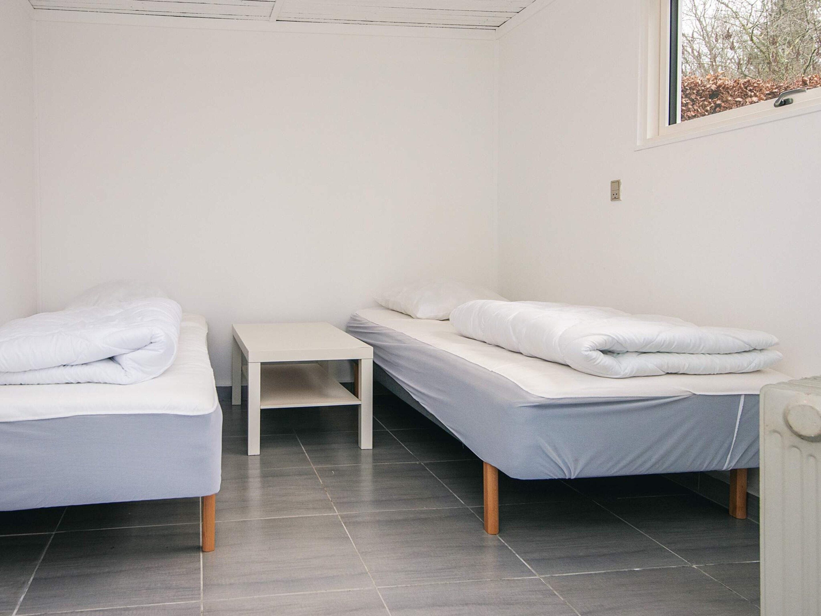 Une chambre avec deux lits simples, une petite table et une fenêtre.