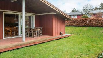 A wooden house with a covered porch and a dining area.
