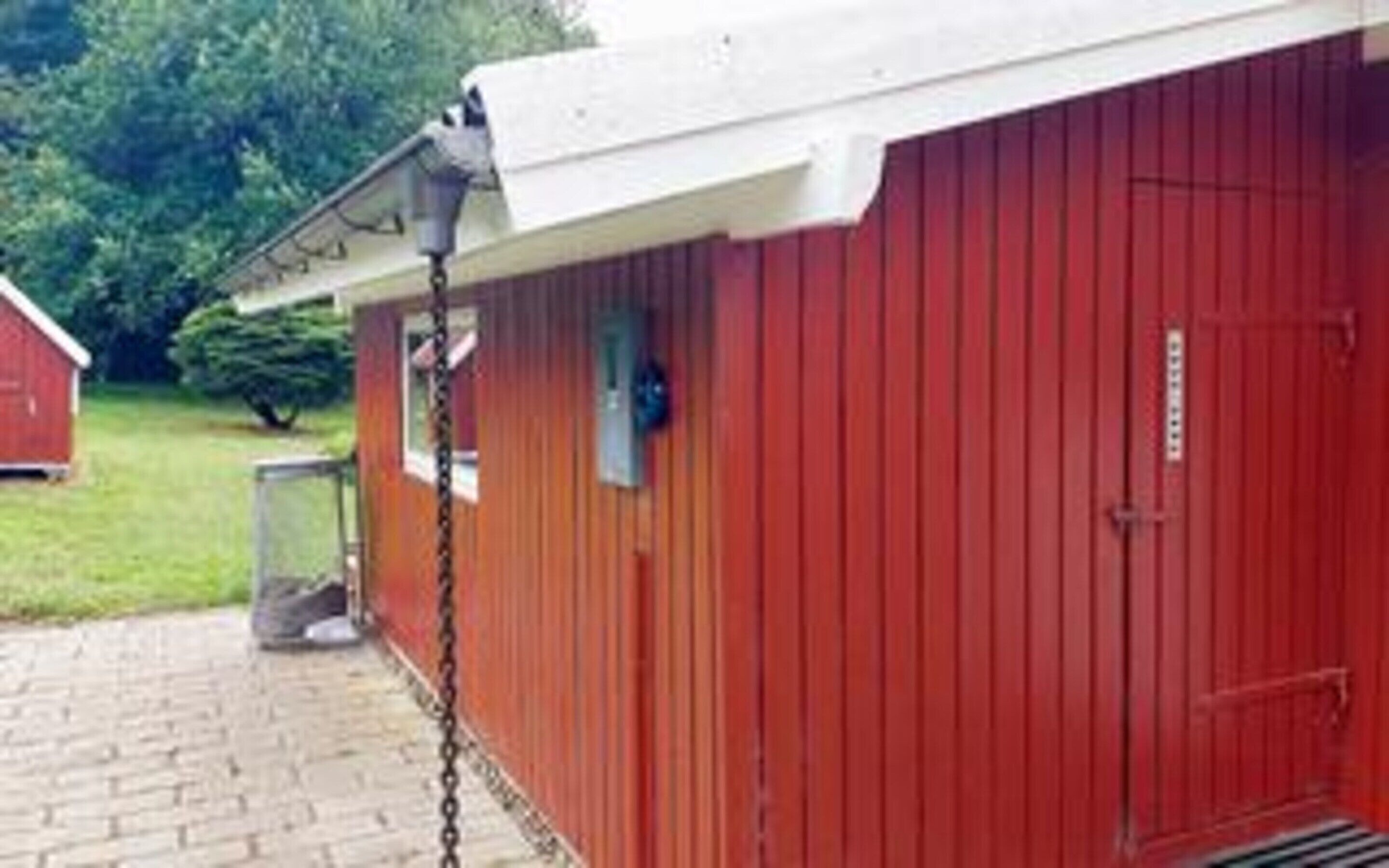 A red building with a white roof, a chain-link fence, and a metal door.