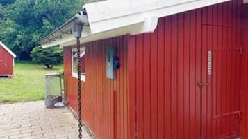 A red building with a white roof, a chain-link fence, and a metal door.
