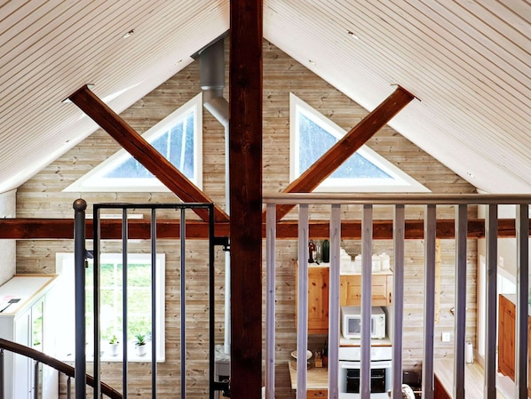 A wooden interior with a high ceiling, exposed beams, and a view of a kitchen area through a glass door. - 6 Person Holiday Home in Vittsjo (Vittsjo)