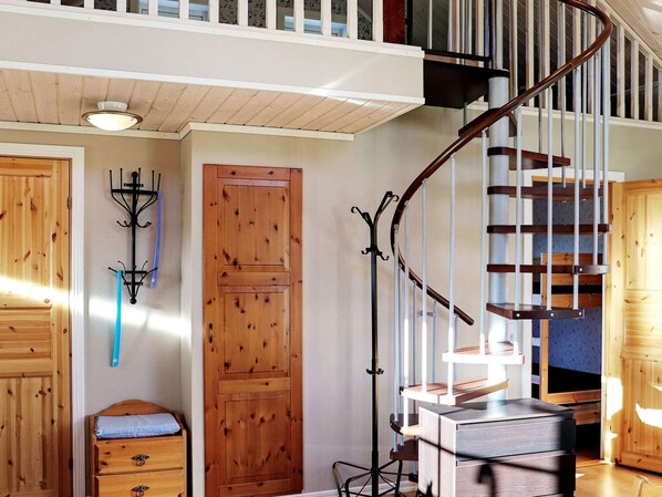 A wooden staircase with a metal handrail, a wooden door, and a coat rack with a blue item hanging on it. - 6 Person Holiday Home in Vittsjo (Vittsjo)