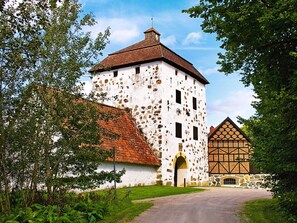 A historic building with a white facade and red-tiled roof, a stone tower, and a traditional timber-framed structure. - 6 Person Holiday Home in Vittsjo (Vittsjo)