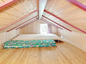 A small attic bedroom with a sloped ceiling, a single bed, and a window with curtains. - Holiday Home in Jerup (Jerup)