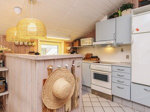 A kitchen with a wooden island, white appliances, and a woven light fixture. - Holiday Home in Jerup (Jerup)