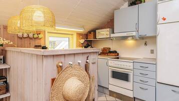 A kitchen with a central island, white cabinetry, a microwave, an oven, and a refrigerator.