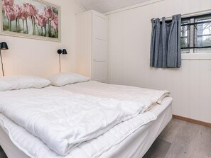 A bedroom with a bed, a painting, a window with curtains, and a door. - Holiday Home in Jerup (Jerup)