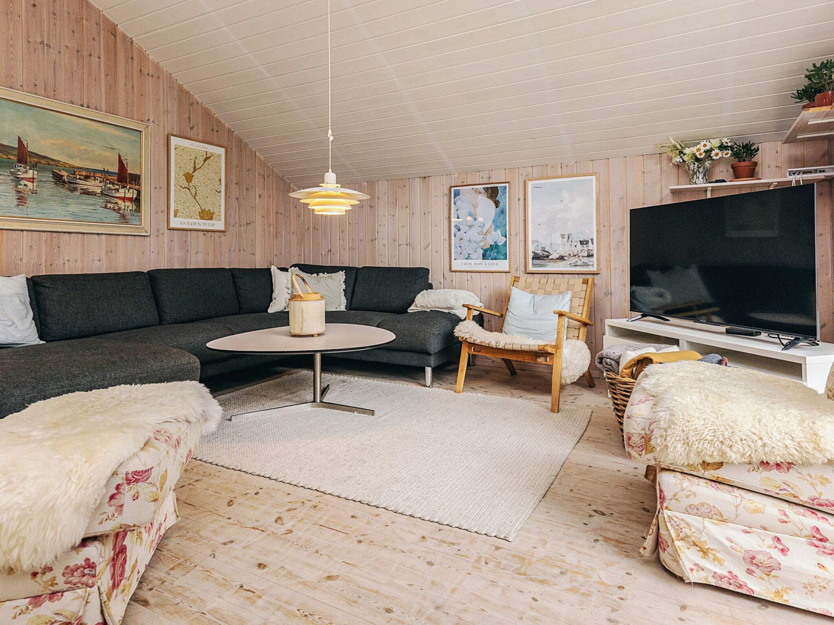A cozy living room with a sofa, armchairs, a coffee table, and a television.