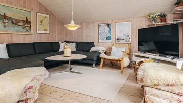 A cozy living room with a sofa, armchairs, a coffee table, and a television.