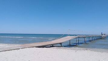 A wooden pier extending into calm waters with a clear sky above.