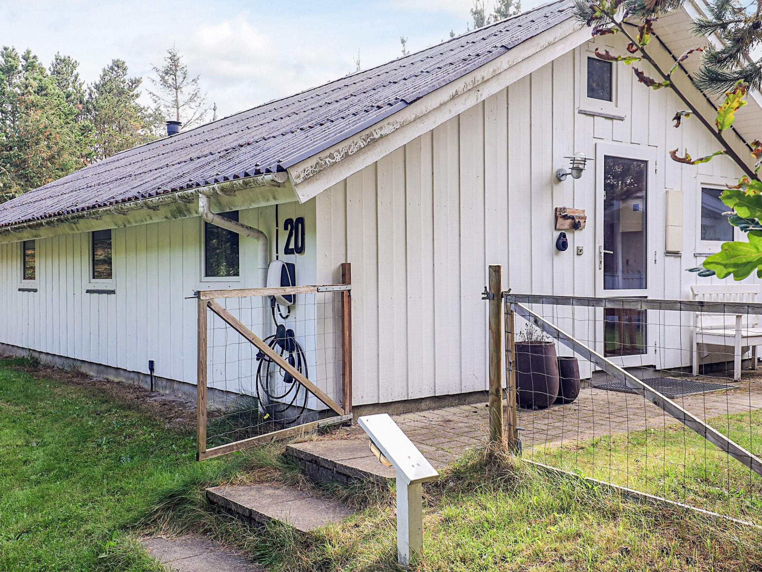 Un bâtiment blanc avec le chiffre « 20 » peint sur le côté, une porte en bois et un petit porche.