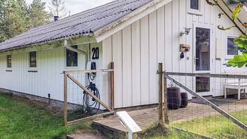 A white building with a number '20' on the side, a wooden door, and a small porch area.