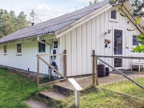 A white building with a number '20' on the side, a wooden door, and a small porch area. - Holiday Home in Jerup (Jerup)