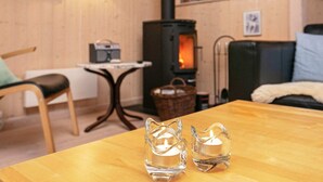 Une pièce chaleureuse avec une table en bois, deux chandeliers en verre, une chaise, un canapé, une cheminée et une radio.