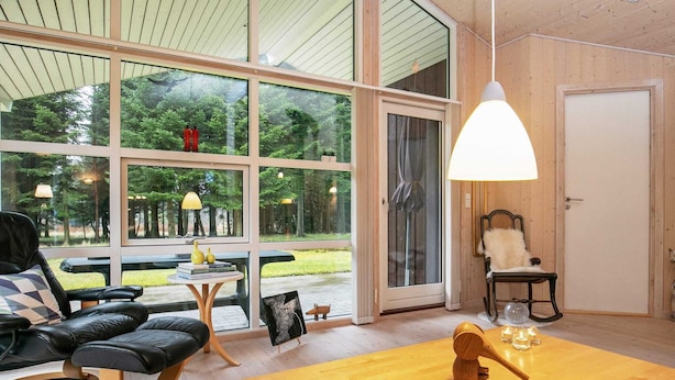 Une pièce spacieuse dotée de grandes fenêtres, d’une table en bois et d’un coin salon confortable.